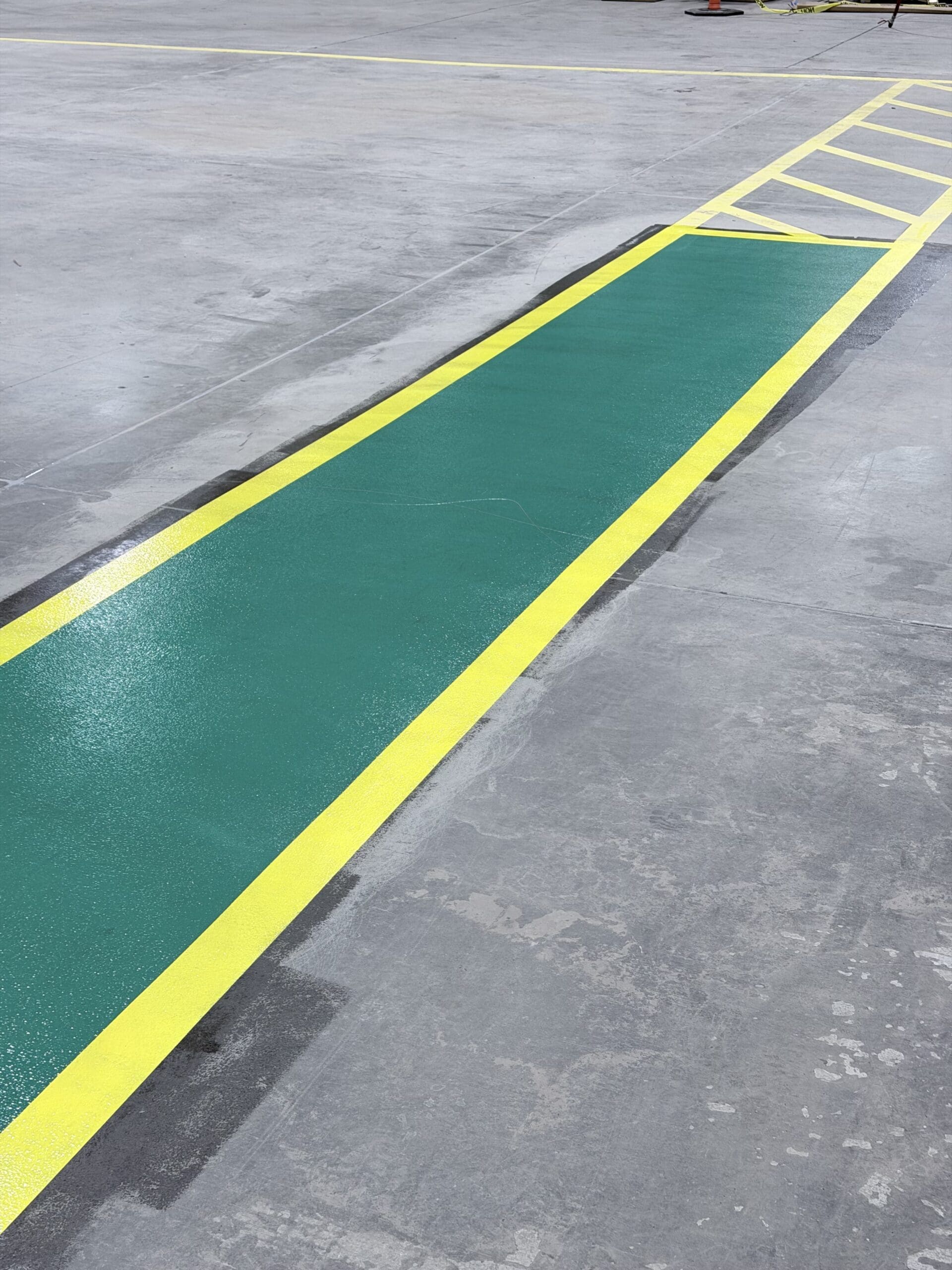 Bright green pedestrian walkway bordered by yellow safety lines