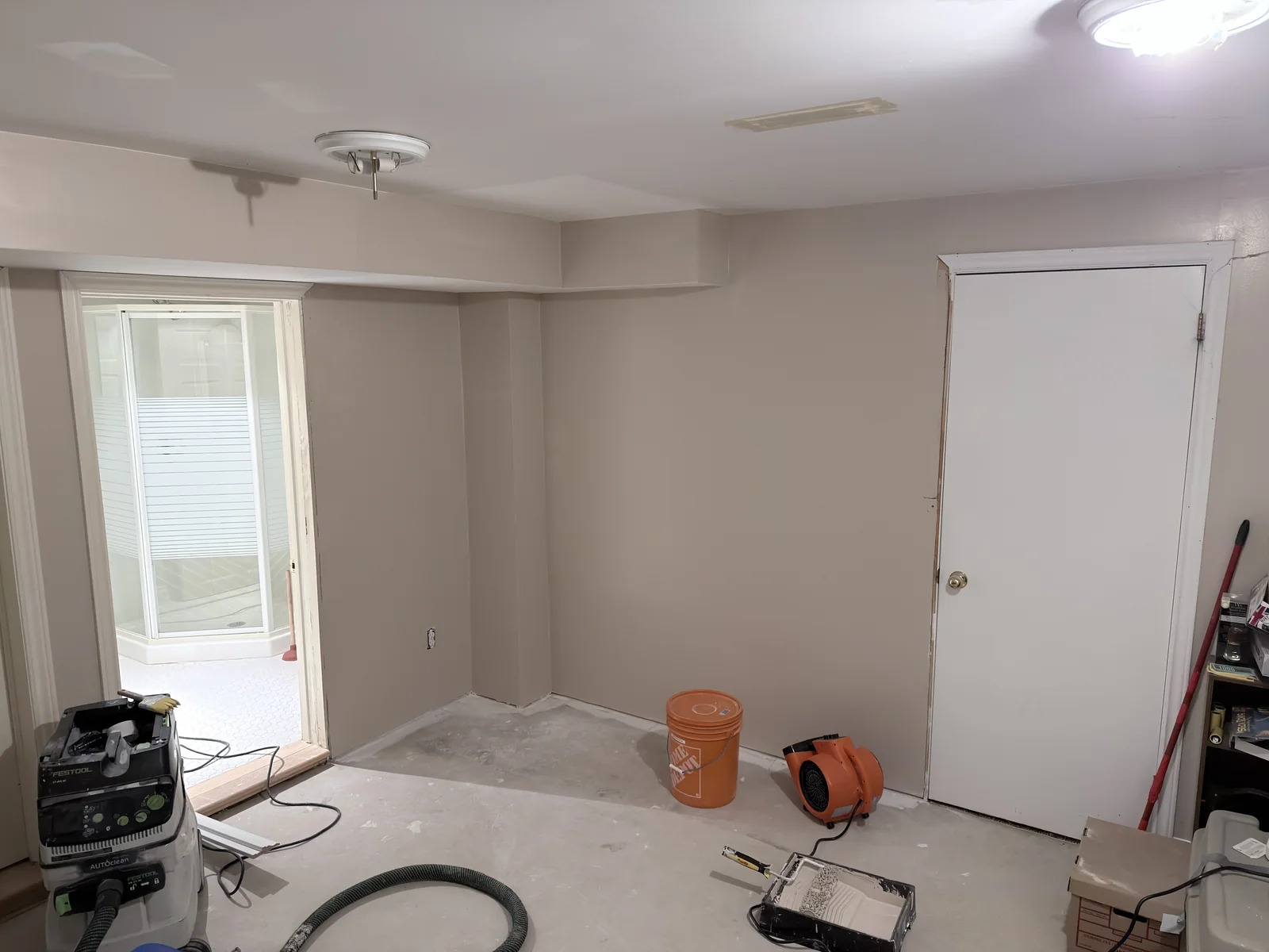 Interior room with drywall finishing work, protected floors and tools